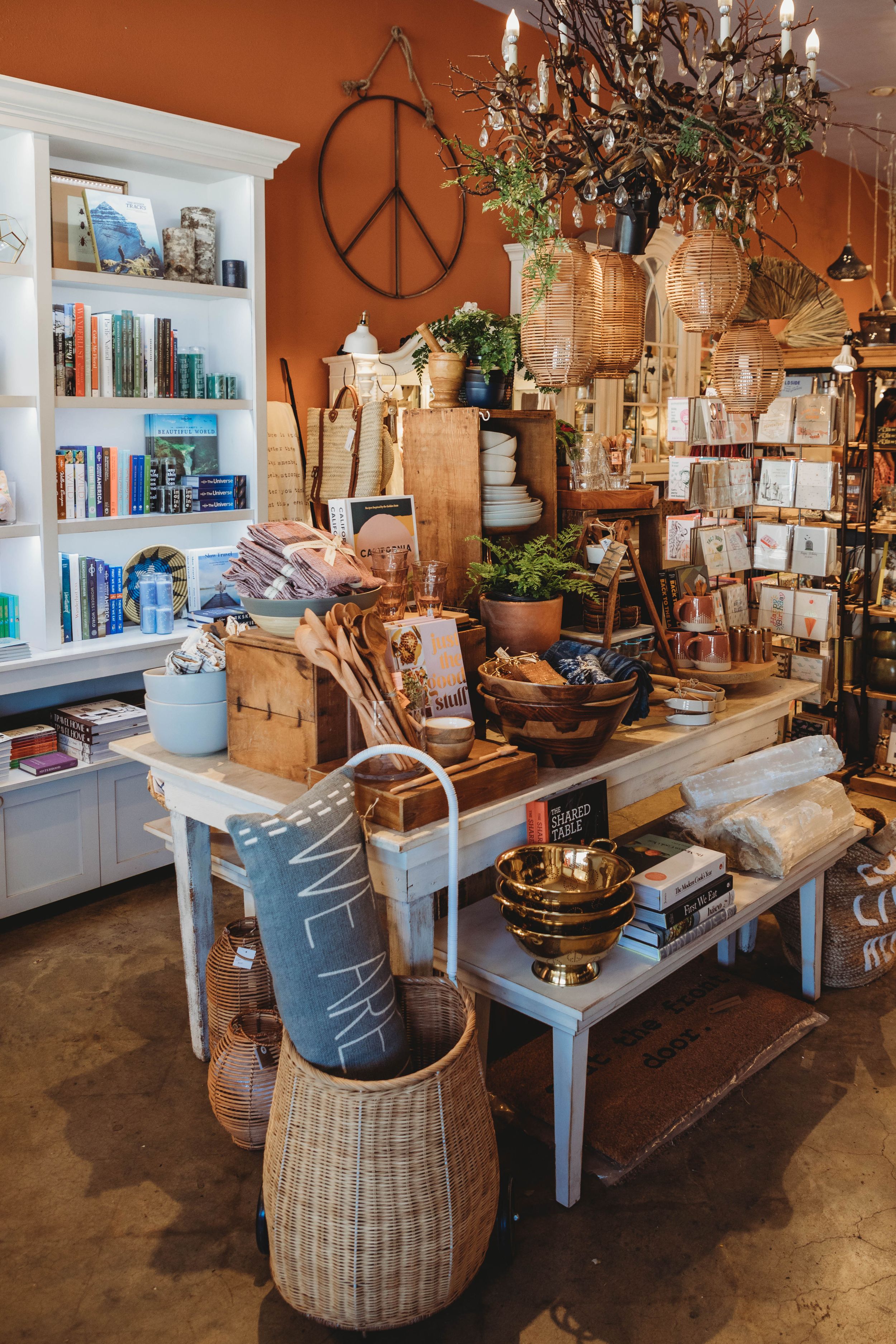Cozy bohemian retail shop interior with bookshelves, peace sign wall art, and rustic decor on display tables.