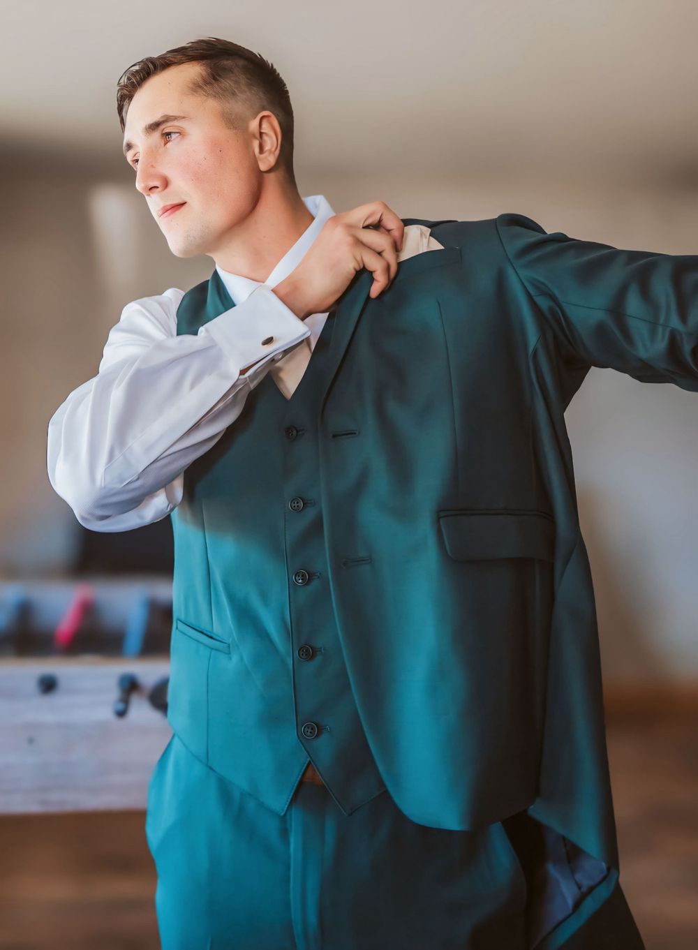 Groom putting on jacket in Maine