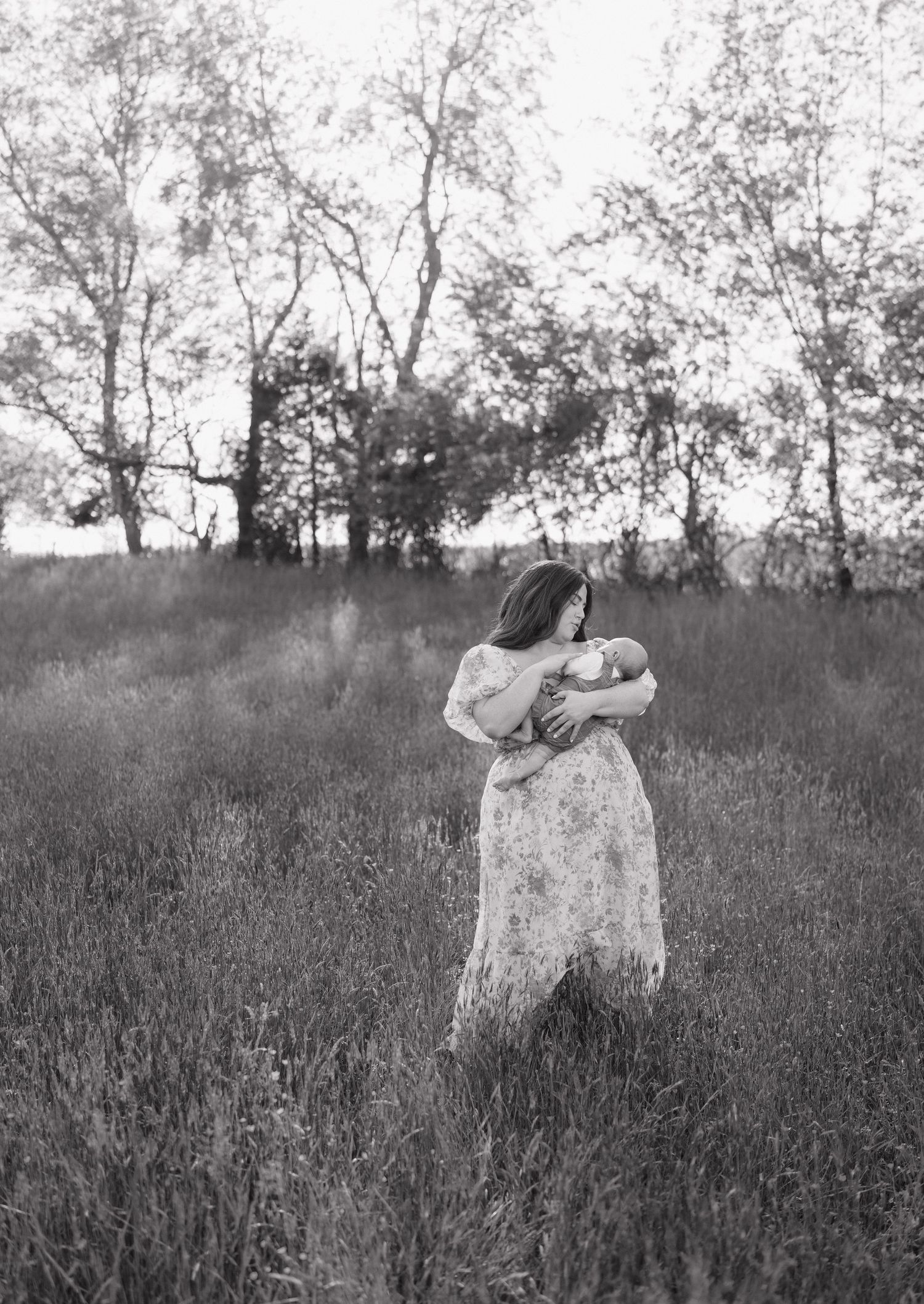 A black and white photograph captures a romantic moment in a misty field surrounded by trees.