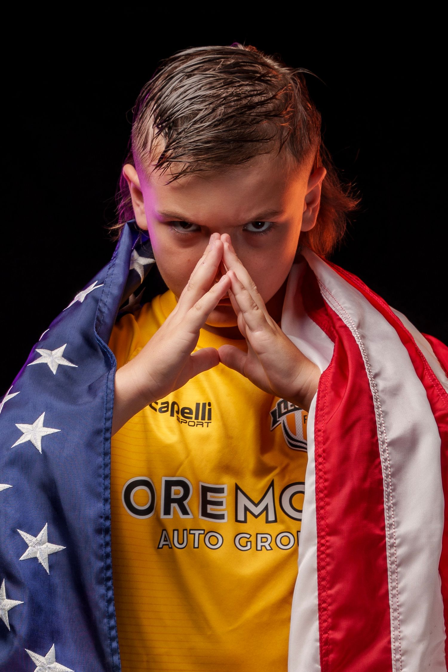 Person wearing yellow jersey draped in American flag against black backdrop.