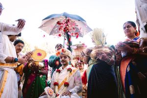 Wedding celebration outdoors with guests holding umbrellas in bright sunlight.