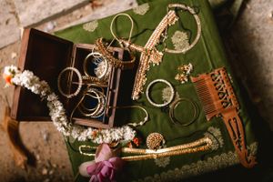Traditional Indian wedding accessories and jewelry arranged on green fabric.