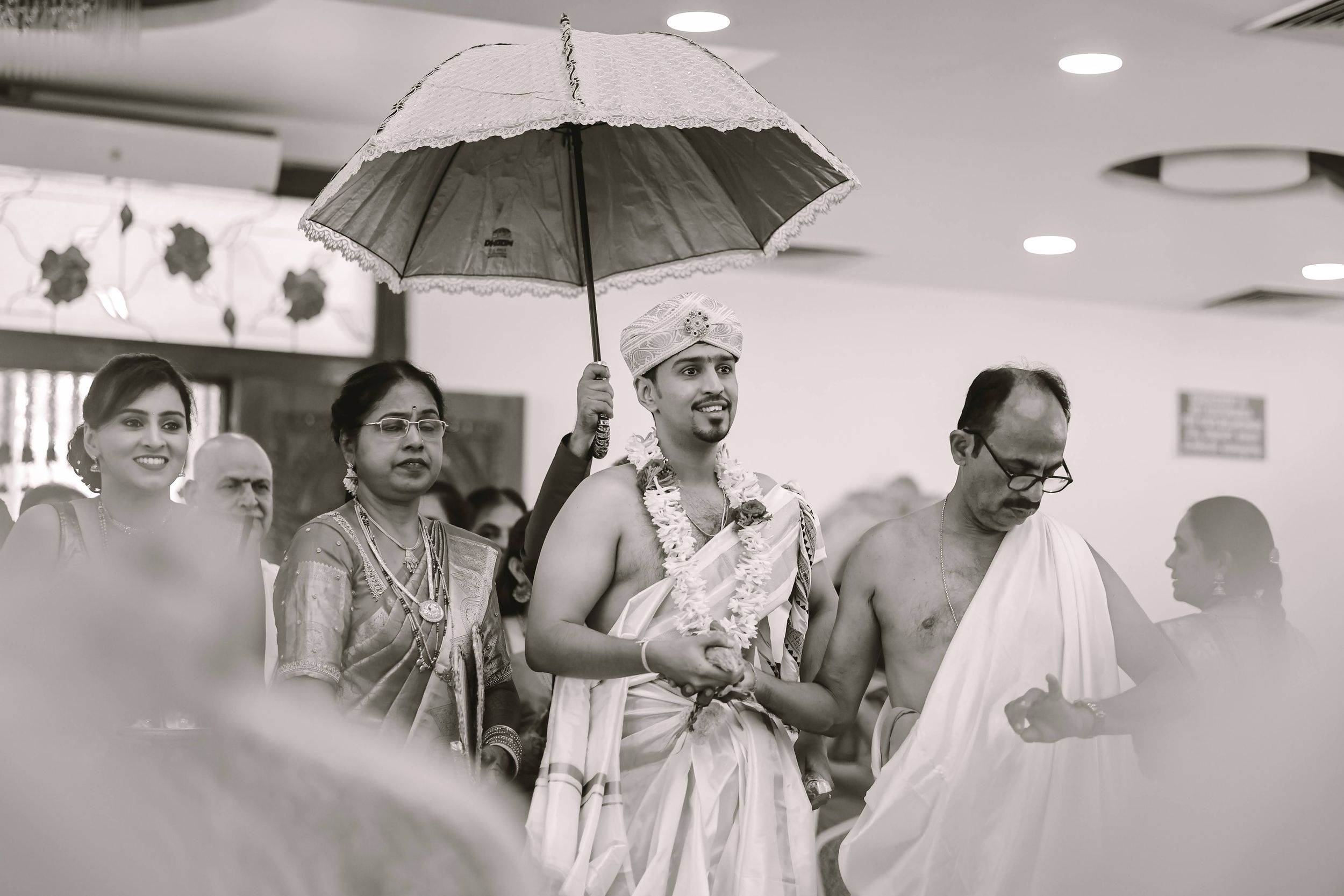 People holding umbrellas indoors during a traditional ceremony.