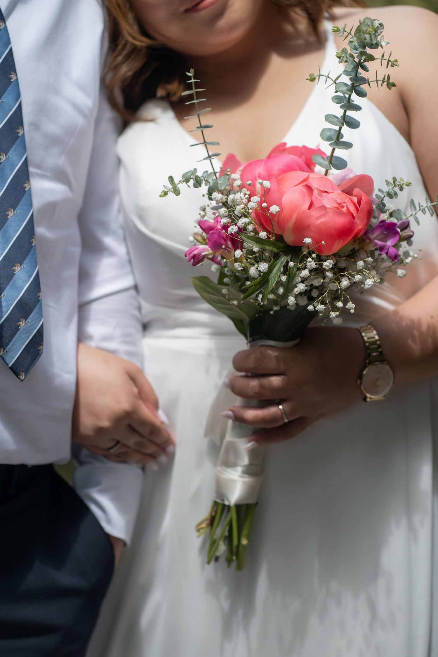 White floral arrangements in metallic vases displayed on outdoor wooden deck.