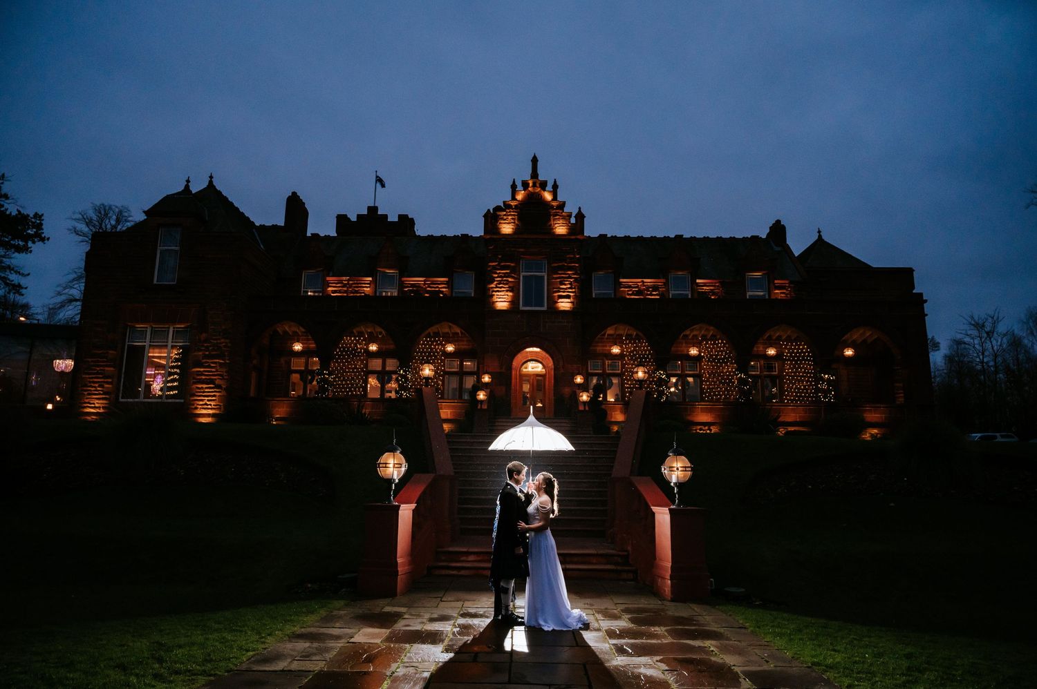 A wedding couple poses on a forest path with the bride's long train flowing behind her.