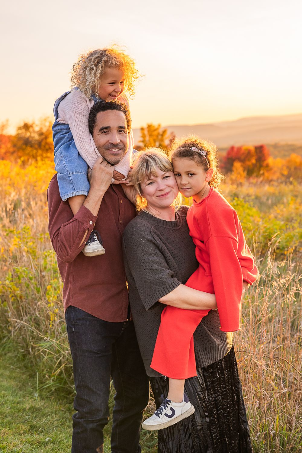 A family shares a joyful embrace during golden hour in a field.