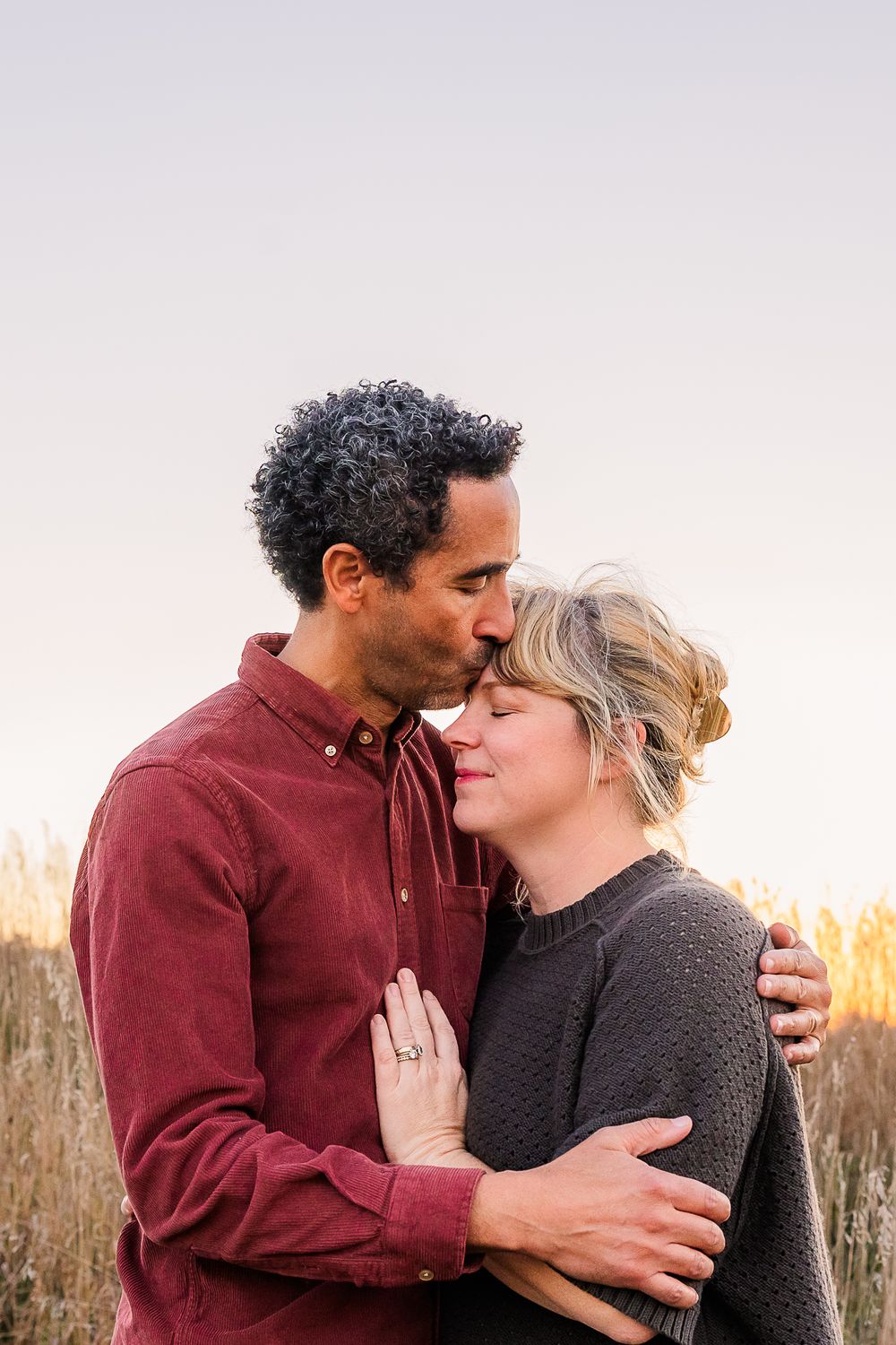 An intimate portrait of a couple sharing a tender moment at sunset.