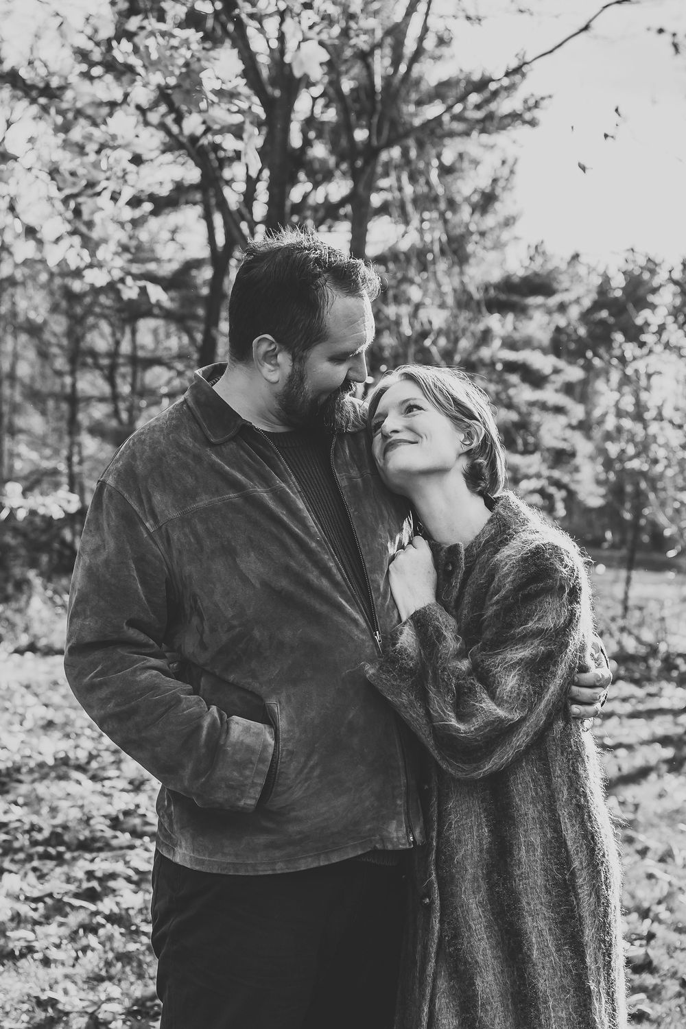 A romantic black and white photo series of a couple embracing outdoors in winter coats.