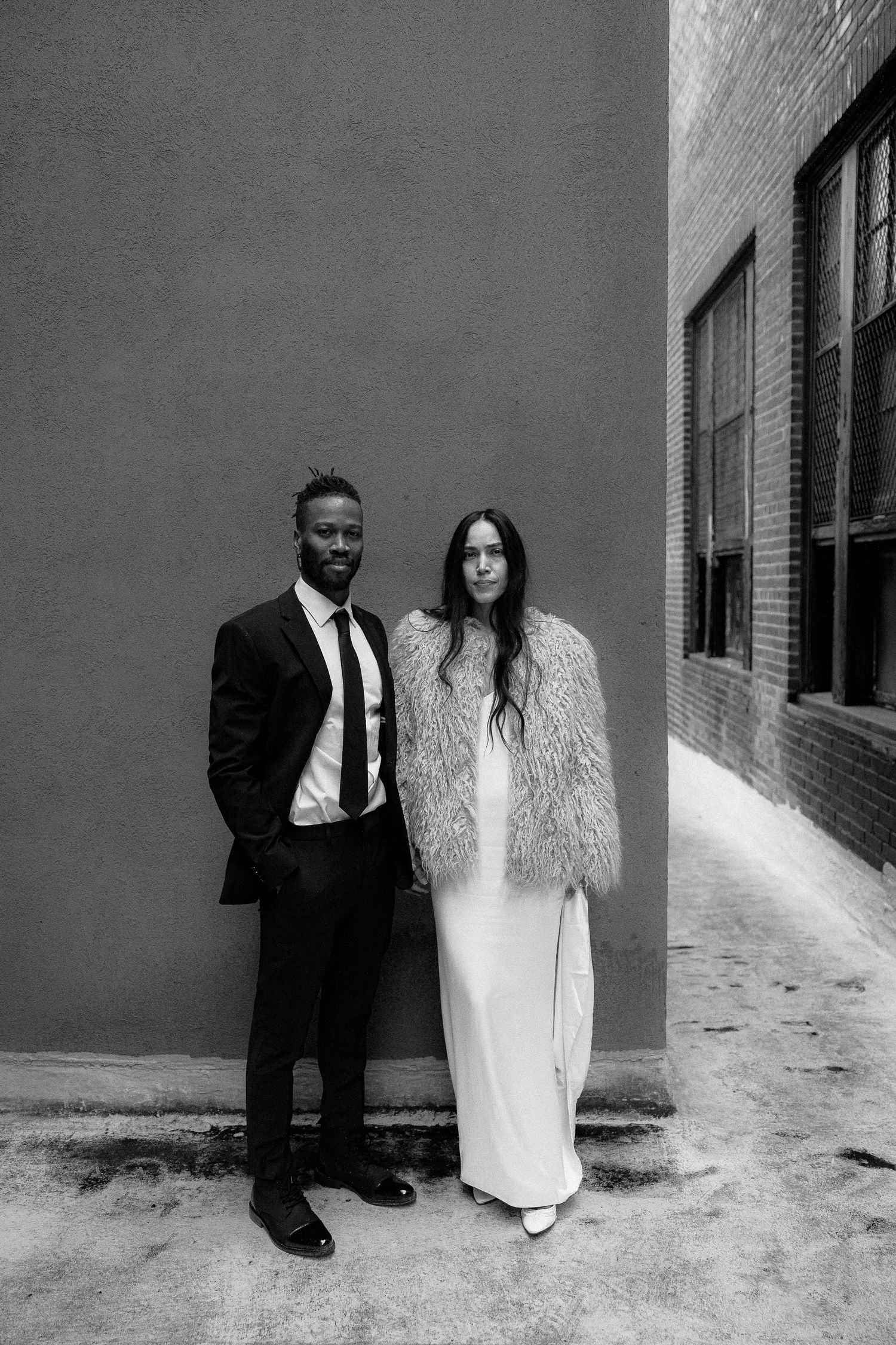 Black and white wedding portrait of an married couple standing against an urban wall. New Bedford Ma. Miranda Photo & Co