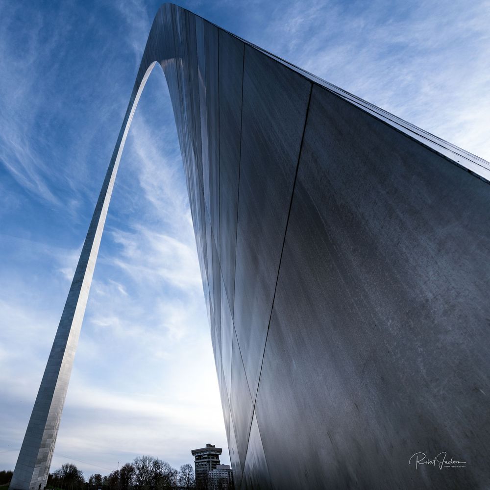 Close-up view of the Gateway Arch in St. Louis, Missouri, with blue sky and wispy clouds in the background.