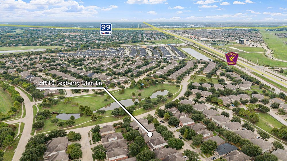 Aerial drone panorama showing residential neighborhoods and roads with green spaces near a suburban development.