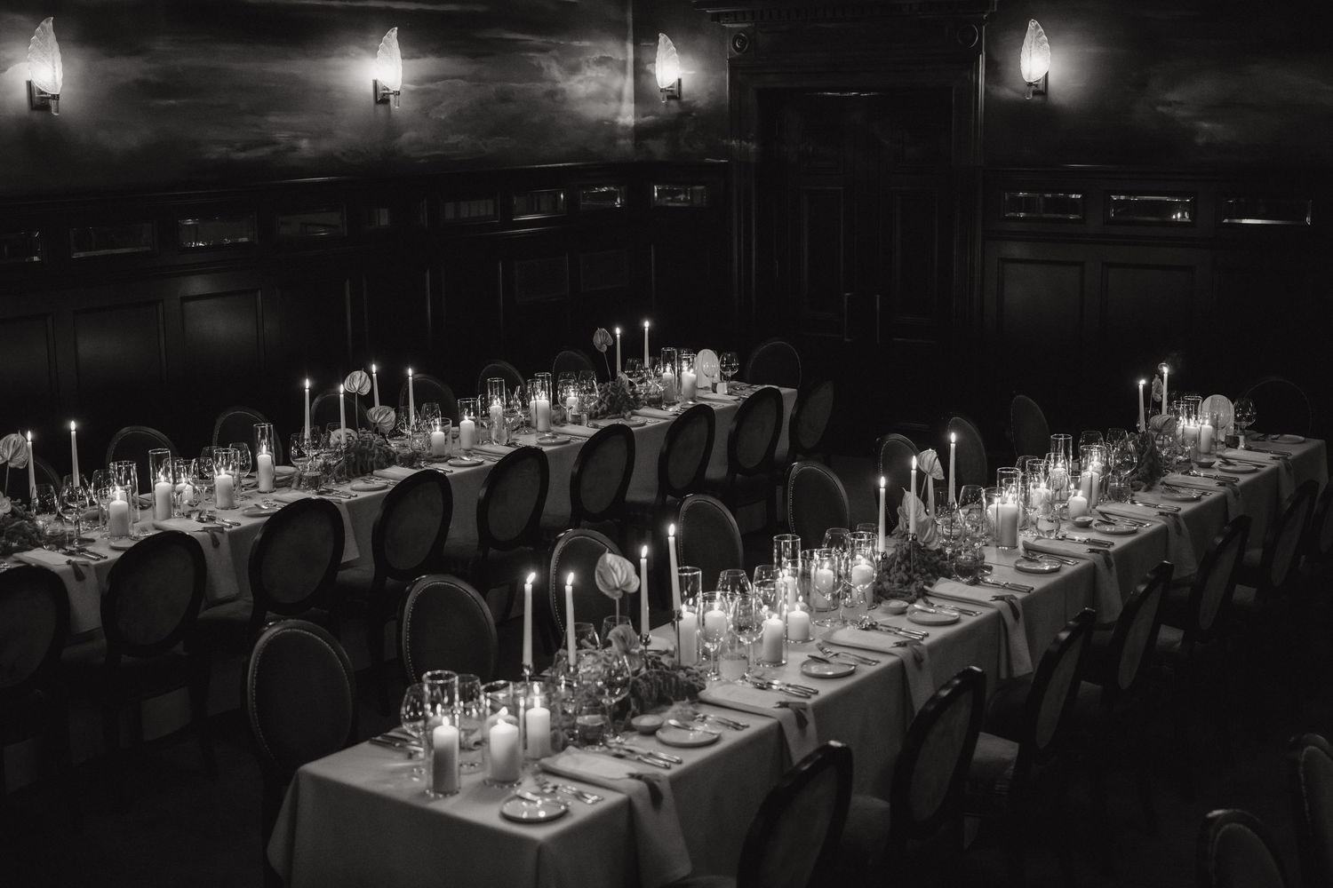 Black and white closeup of a couple toasting with champagne glasses at a wedding reception.