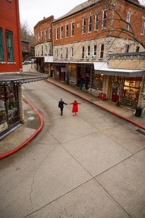 Two people walking down a historic shopping street with red brick buildings and storefronts.