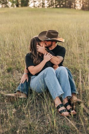 Romantic moment shared between couple sitting in golden meadow at sunset.