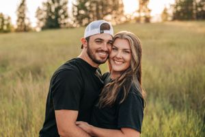 A happy couple shares a tender moment in a summer field during golden hour.