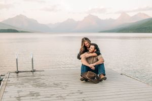 A couple shares an intimate moment on a wooden dock overlooking a mountain lake.