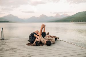 A couple relaxes together on a dock overlooking a serene mountain lake.
