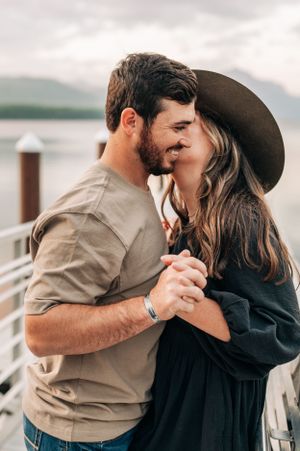 A couple dancing and embracing on a wooden pier with misty mountains in the background.