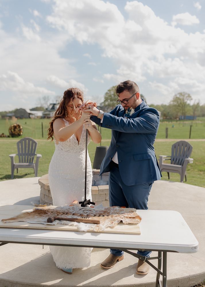 Couple sharing a playful moment while cutting their wedding cake outdoors.