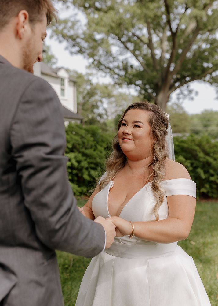 A couple shares a joyful moment in their wedding attire against a natural outdoor backdrop.