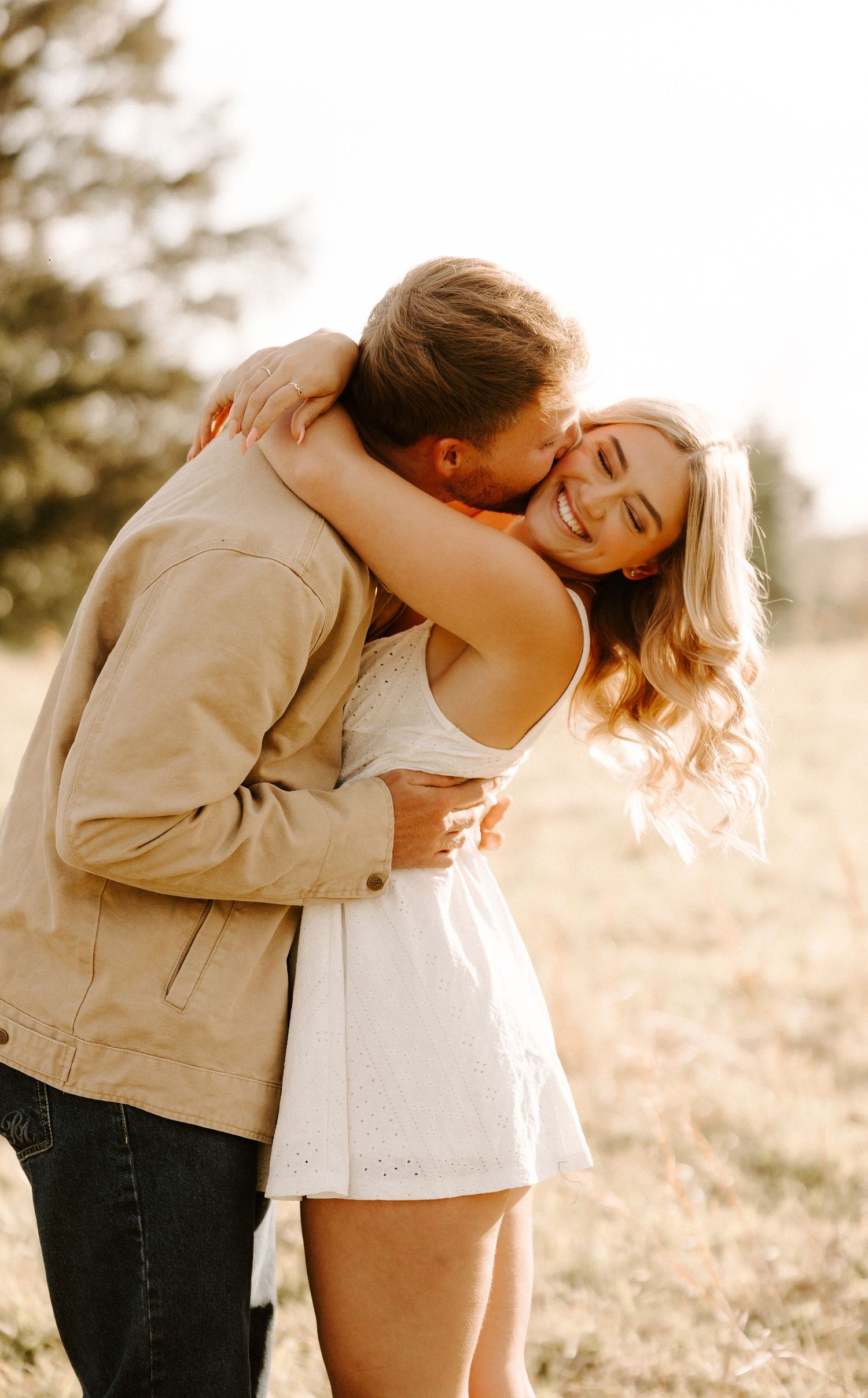 Romantic couple embracing in sunlit field during golden hour in Gallatin, TN.