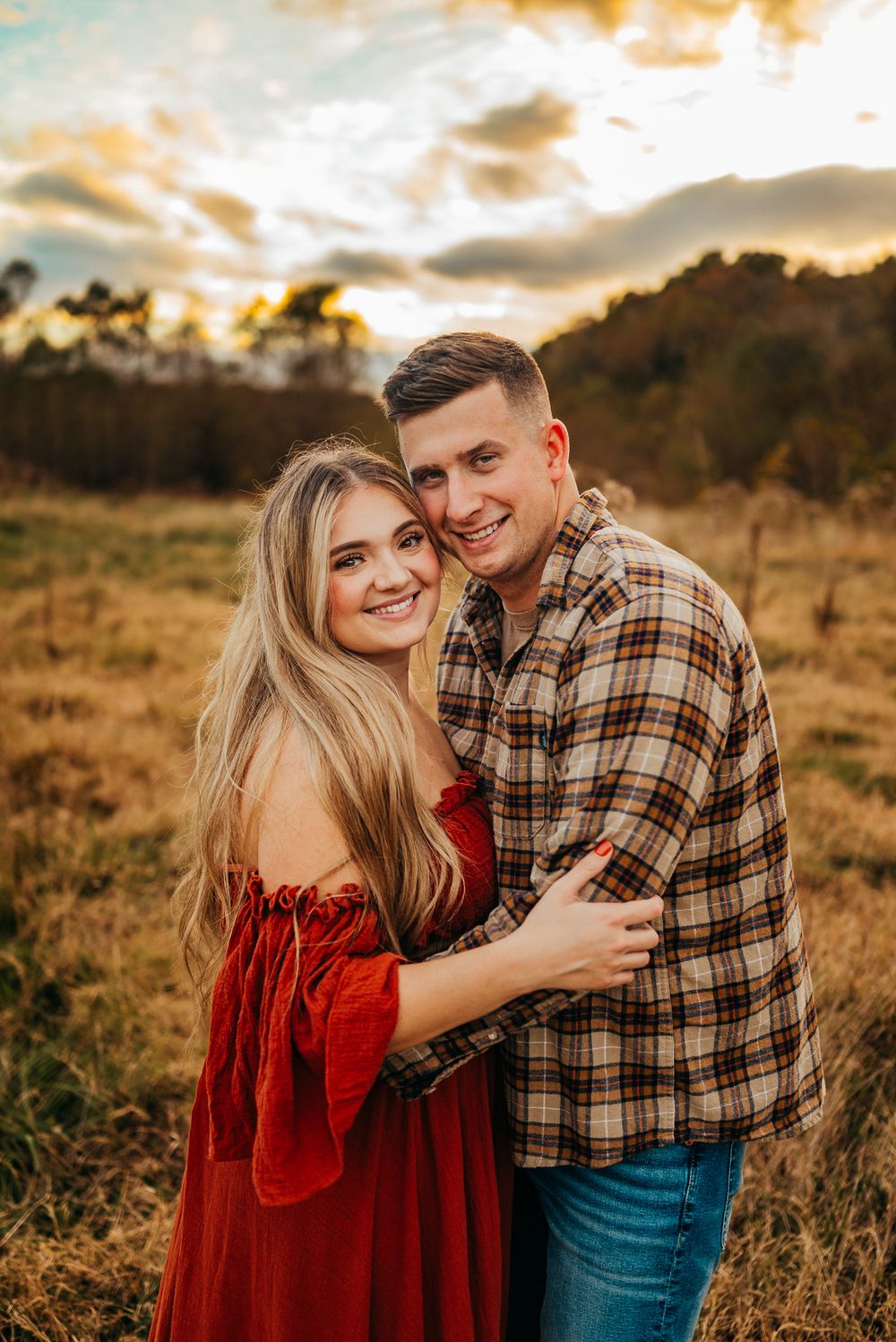 A couple embraces while sharing a romantic moment during sunset in a golden field.