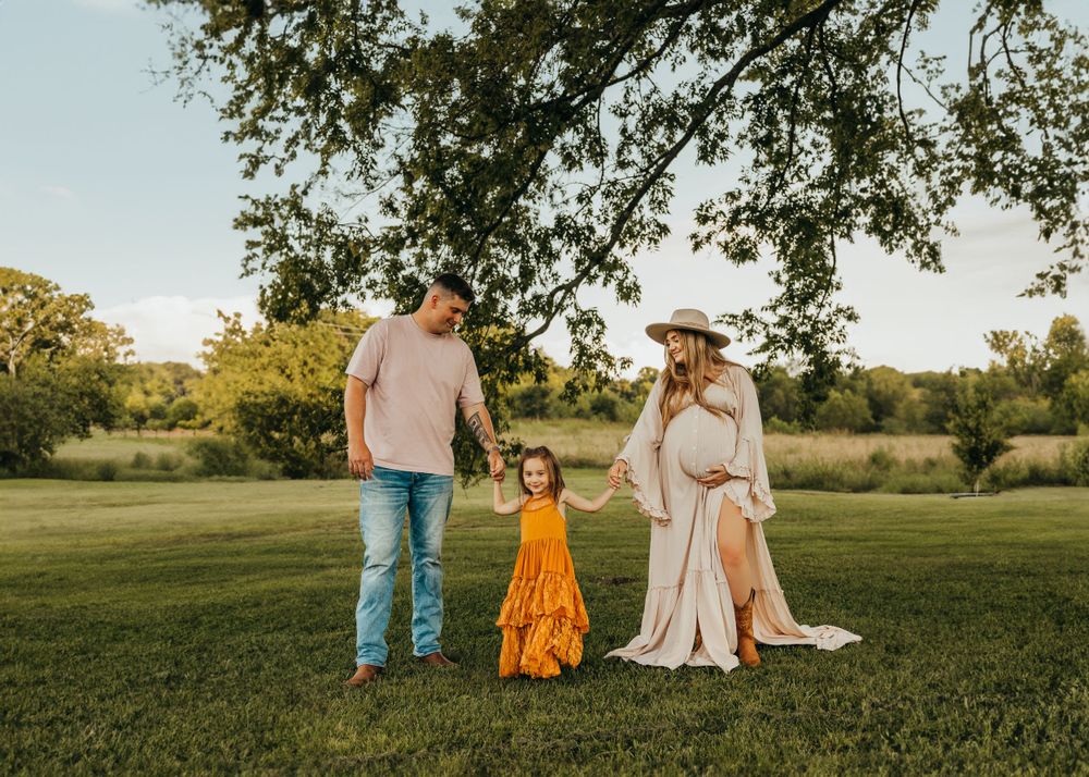 A family poses together on grassy field during golden hour sunset.