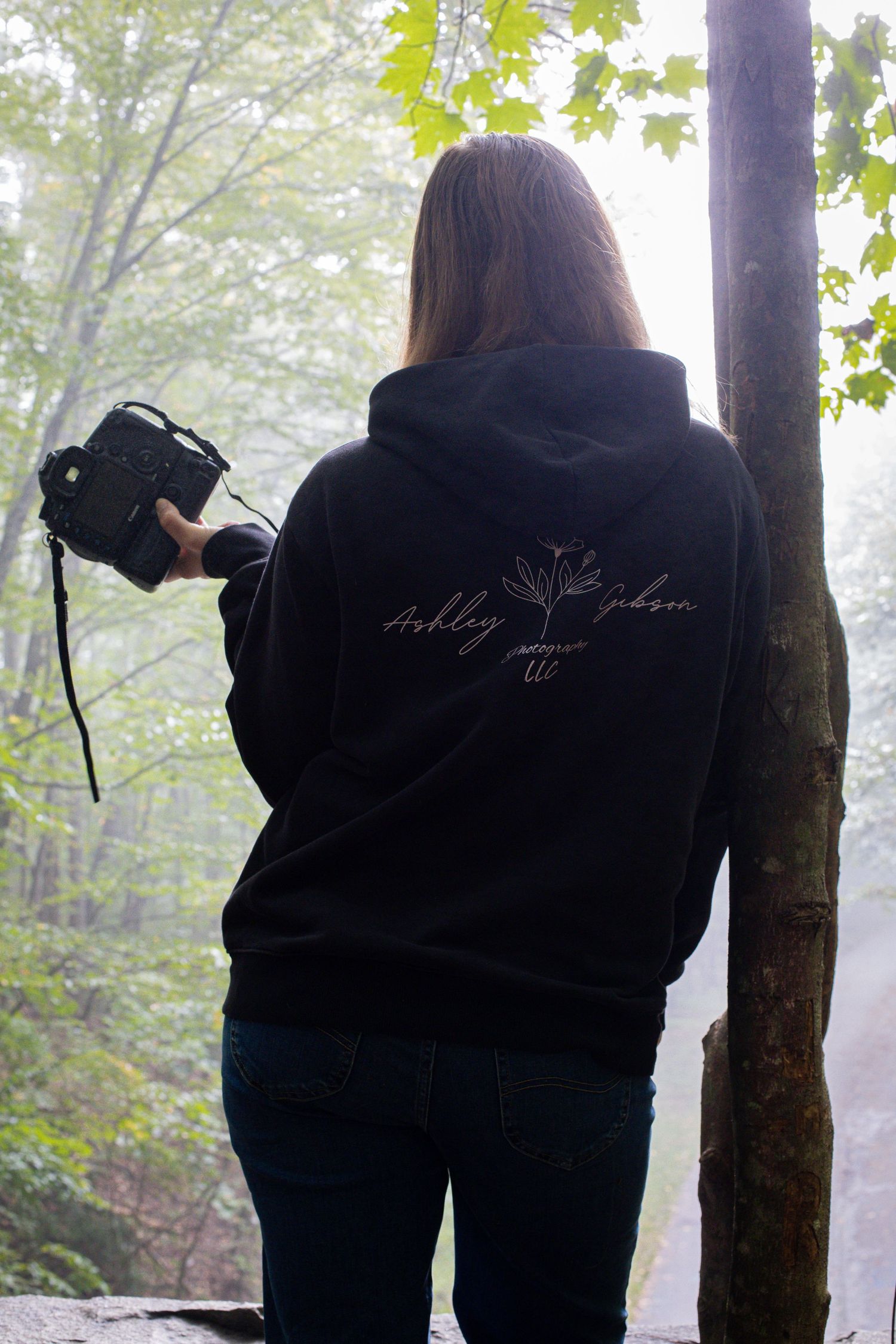 Black and white portrait of a photographer taking pictures outdoors in a knit sweater.