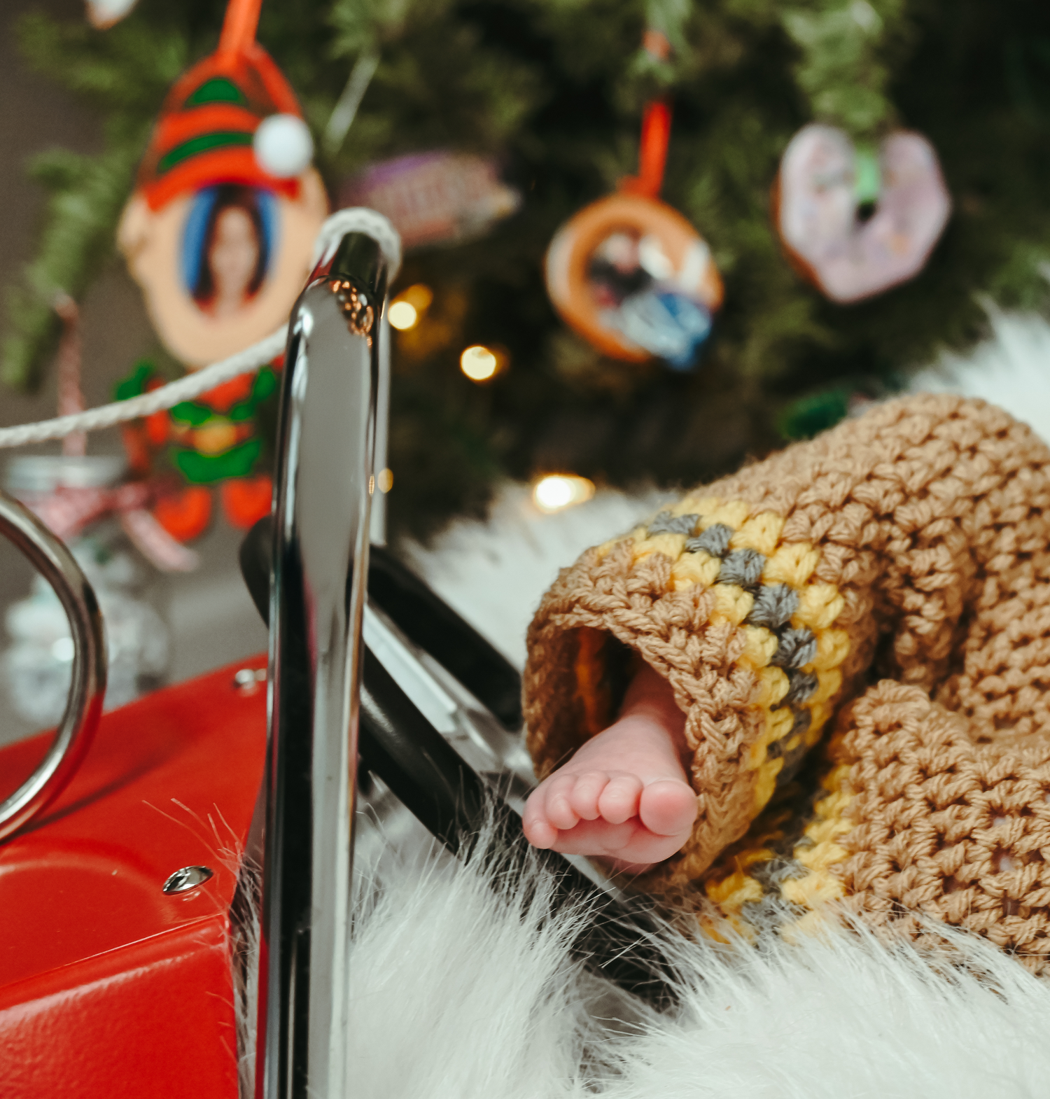 A cozy sleeping baby bundled in a knit sweater near festive Christmas decorations.