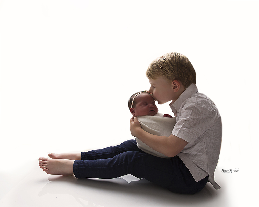 big brother holding newborn baby sister in Melbourne east affordable photography studio in Croydon