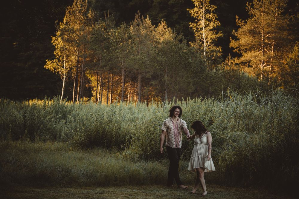 Wedding couple walks through a golden-lit forest at sunset creating a romantic autumn atmosphere.