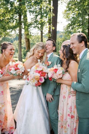 Bride and groom laugh with wedding party, bridesmaids in floral dresses holding colorful bouquets at little river farms in milton georgia