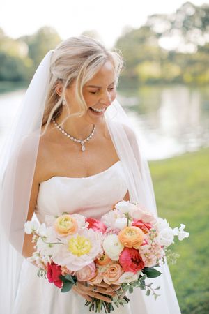 Smiling bride in white strapless gown and veil near a serene lake at little river farms in milton ga