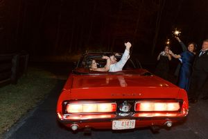 Bride and groom celebrating in a classic red convertible Mustang with sparklers during exit at blue mountain vineyards in dahlonega georgia