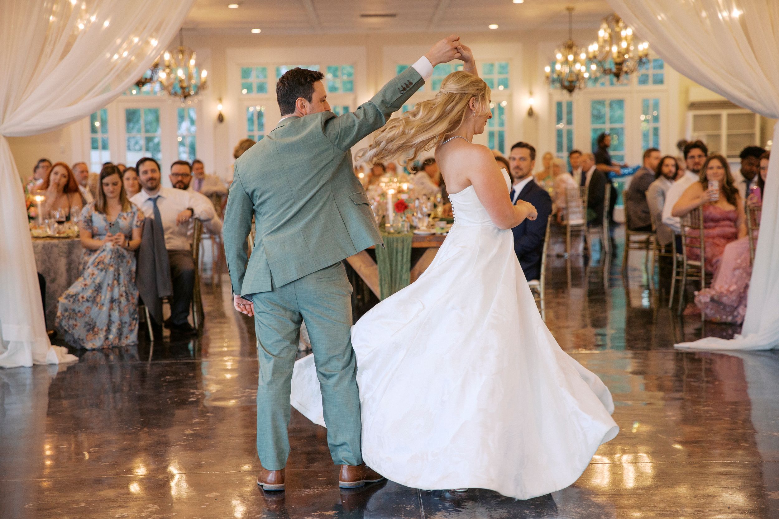 Bride and groom share first dance at elegant wedding reception with guests watching in decorated ballroom at little river farms in milton ga