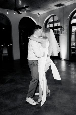 Black and white photo of a bride and groom sharing their last dance, embracing and kissing at montaluce winery in dahlonega georgia