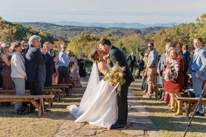 Bride and groom share a kiss at outdoor fall wedding ceremony with scenic mountain views at blue mountain vineyards in dahlonega georgia