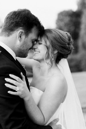 Black and white photo of a smiling bride and groom touching foreheads in a tender romantic embrace on their wedding day at blue mountain
