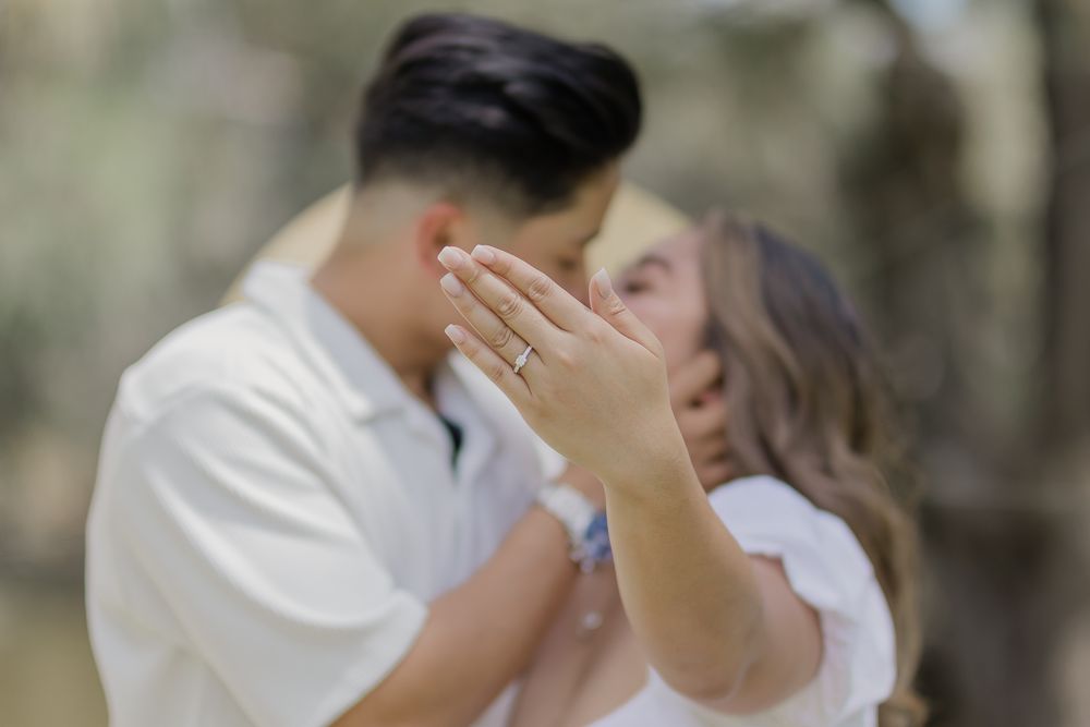 Couple embracing during outdoor engagement photoshoot while showing off new ring.
