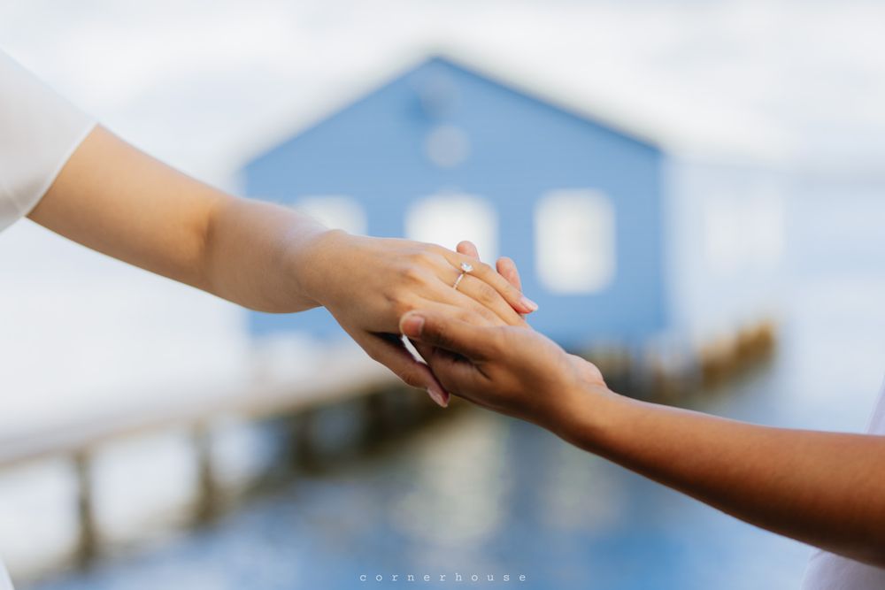 Two hands reaching out to hold each other against a blurry blue background with soft focus.