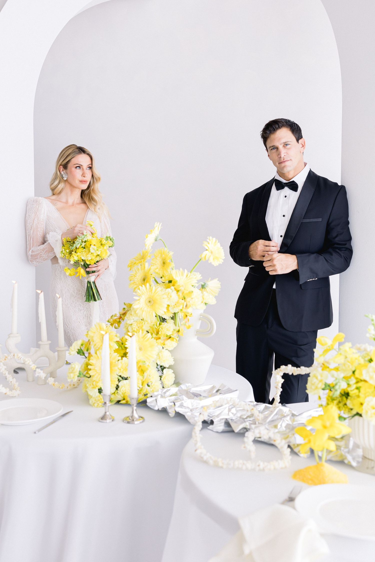 Elegant wedding reception table with yellow floral arrangements and white decor.
