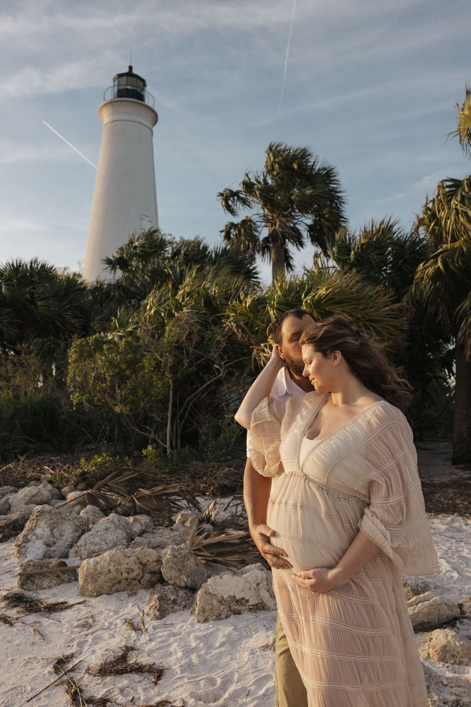 A lighthouse along a rocky beach shore with palm trees and natural coastal scenery in multiple connected photos.
