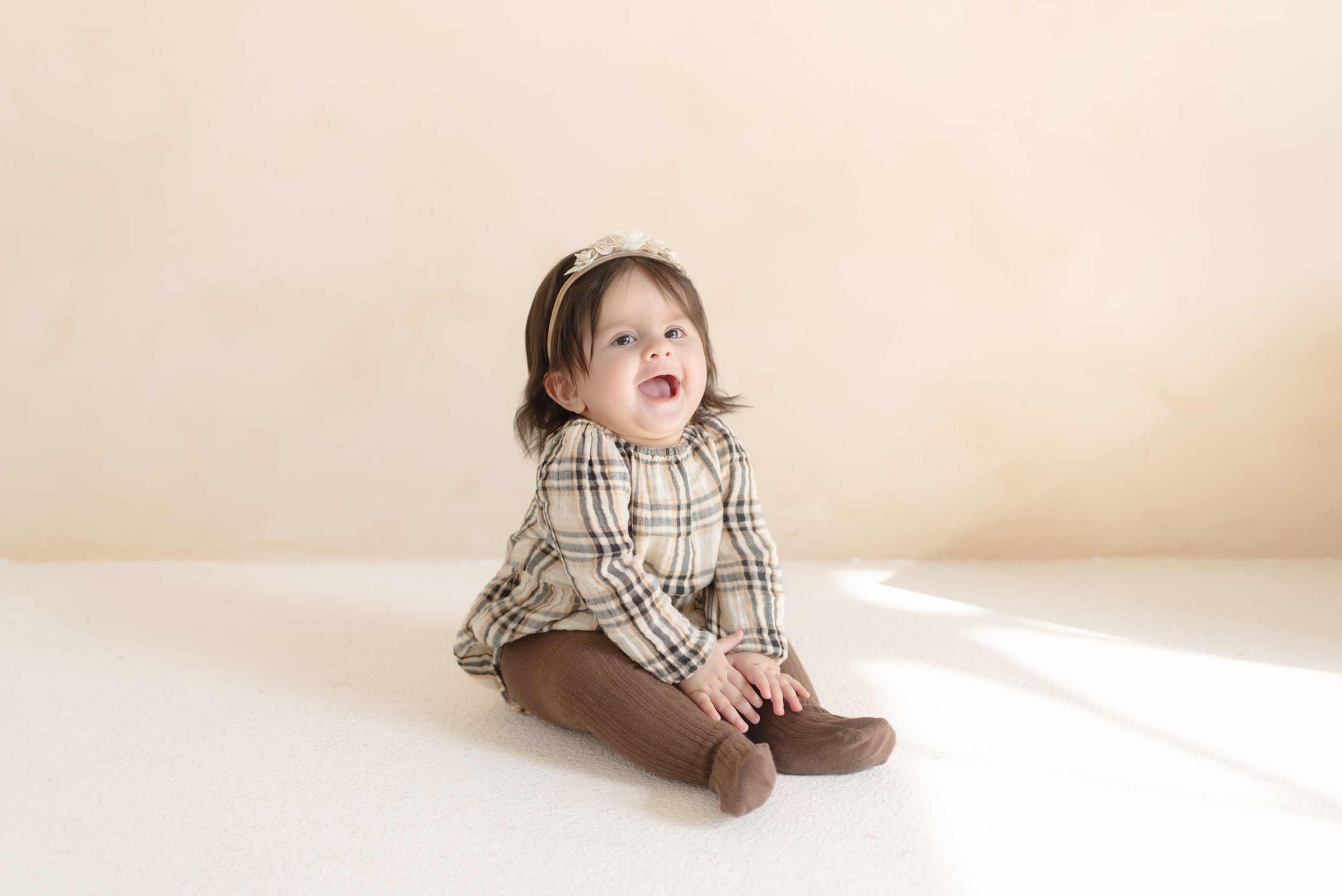 Baby Girl smiling while sitting at a bright and airy studio for Toronto photo session by photographer Jess GC Photography.