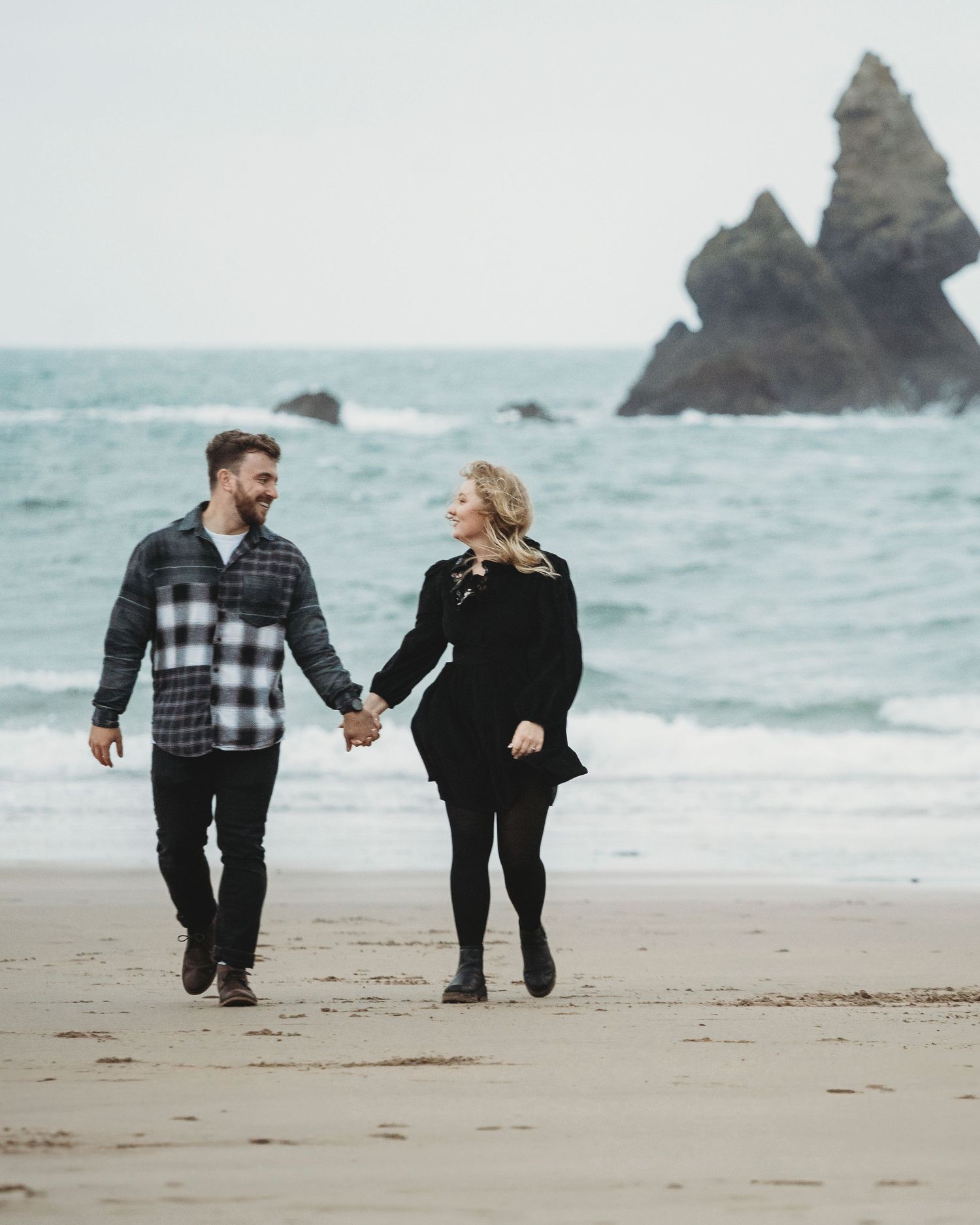 A romantic couple walking hand-in-hand during a sunset engagement session at Bosherston, Pembrokeshire.