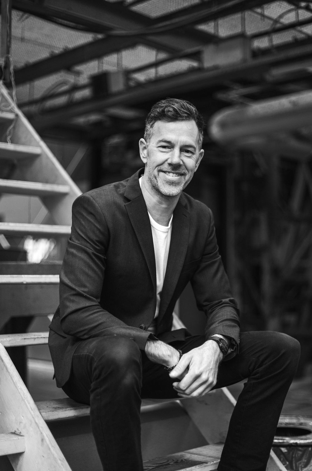 A black and white photo sequence showing someone sitting on steps while wearing a dark suit and white shirt.