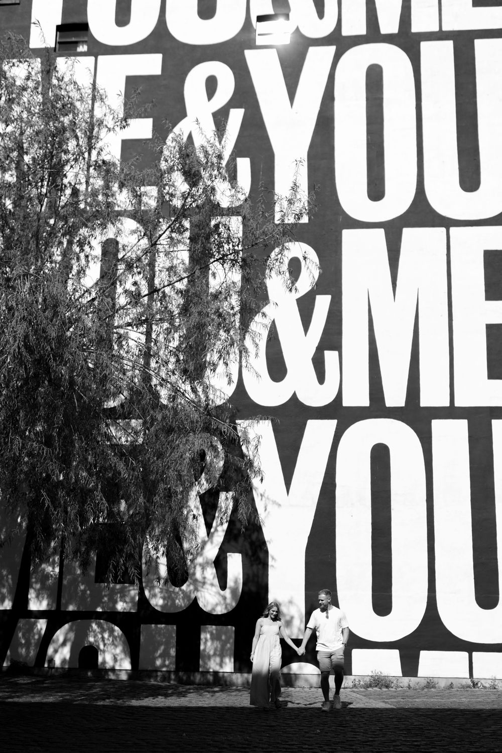 Large white typographic text installation displaying a repeated word pattern in an outdoor wooded setting. Leeds City Centre Pre Wedding.