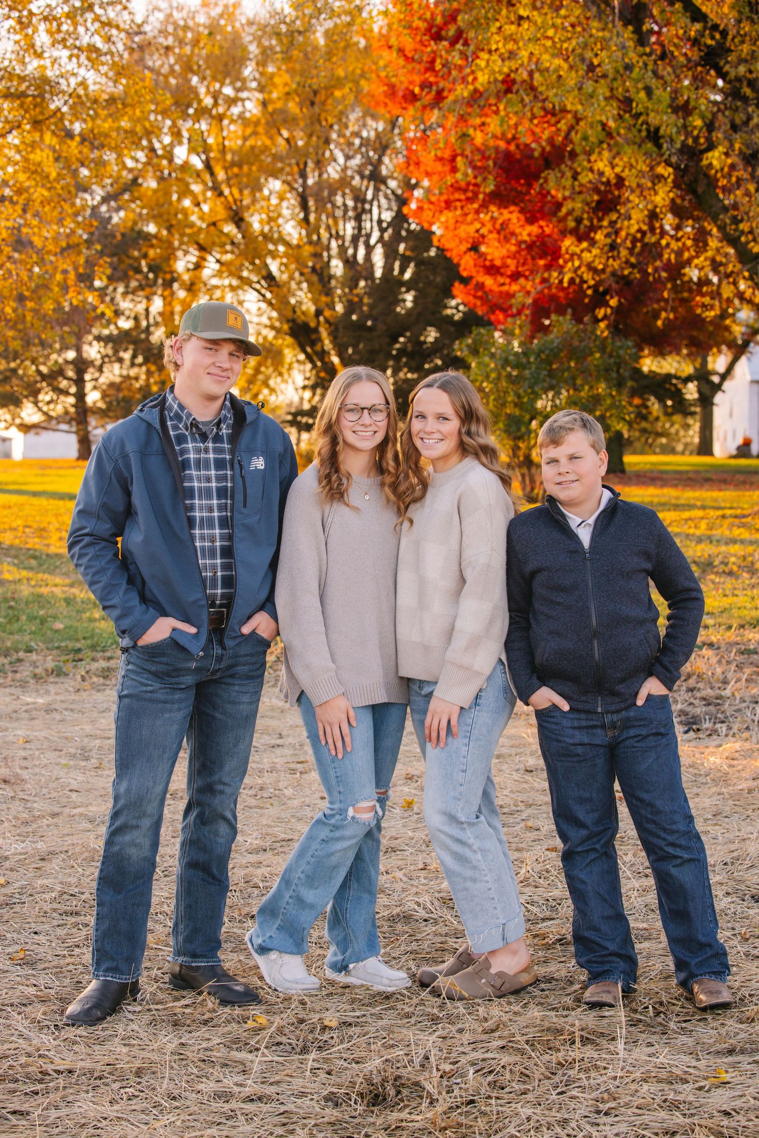 Casual outdoor family portrait in front of a red barn during fall season.