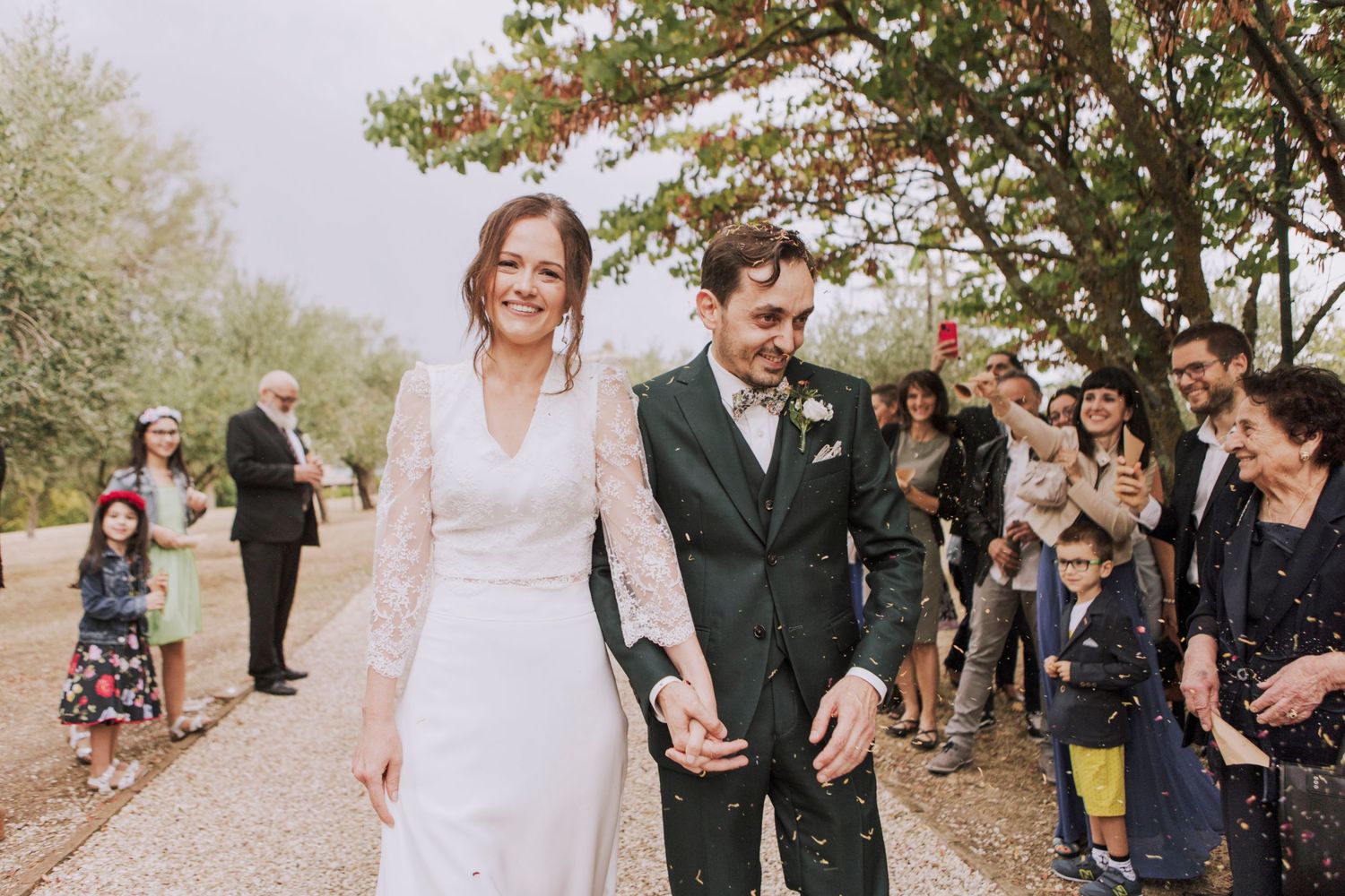 Happy couple walks hand in hand on outdoor path during wedding celebration.