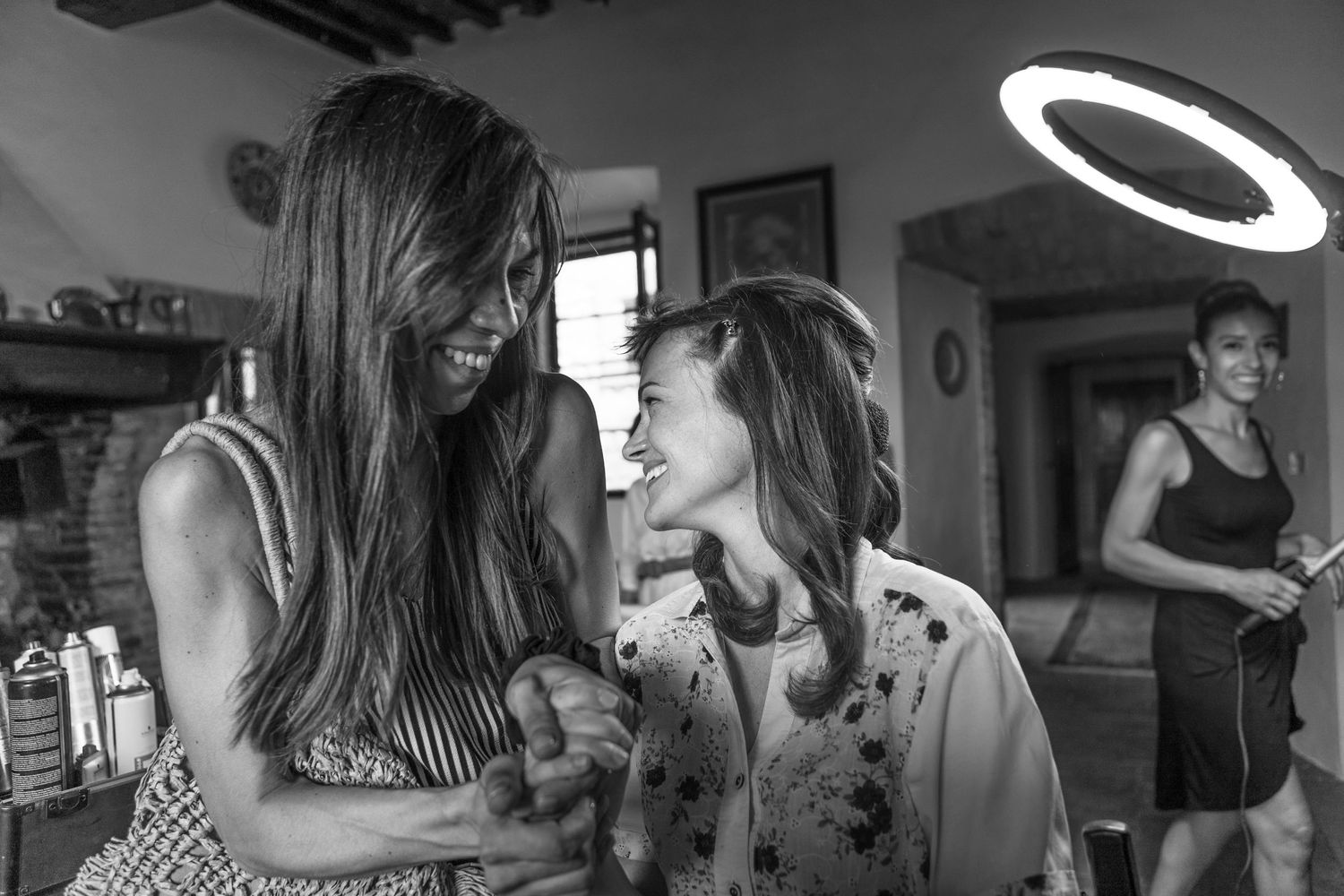 Black and white candid moment during wedding preparations with ring light in background.
