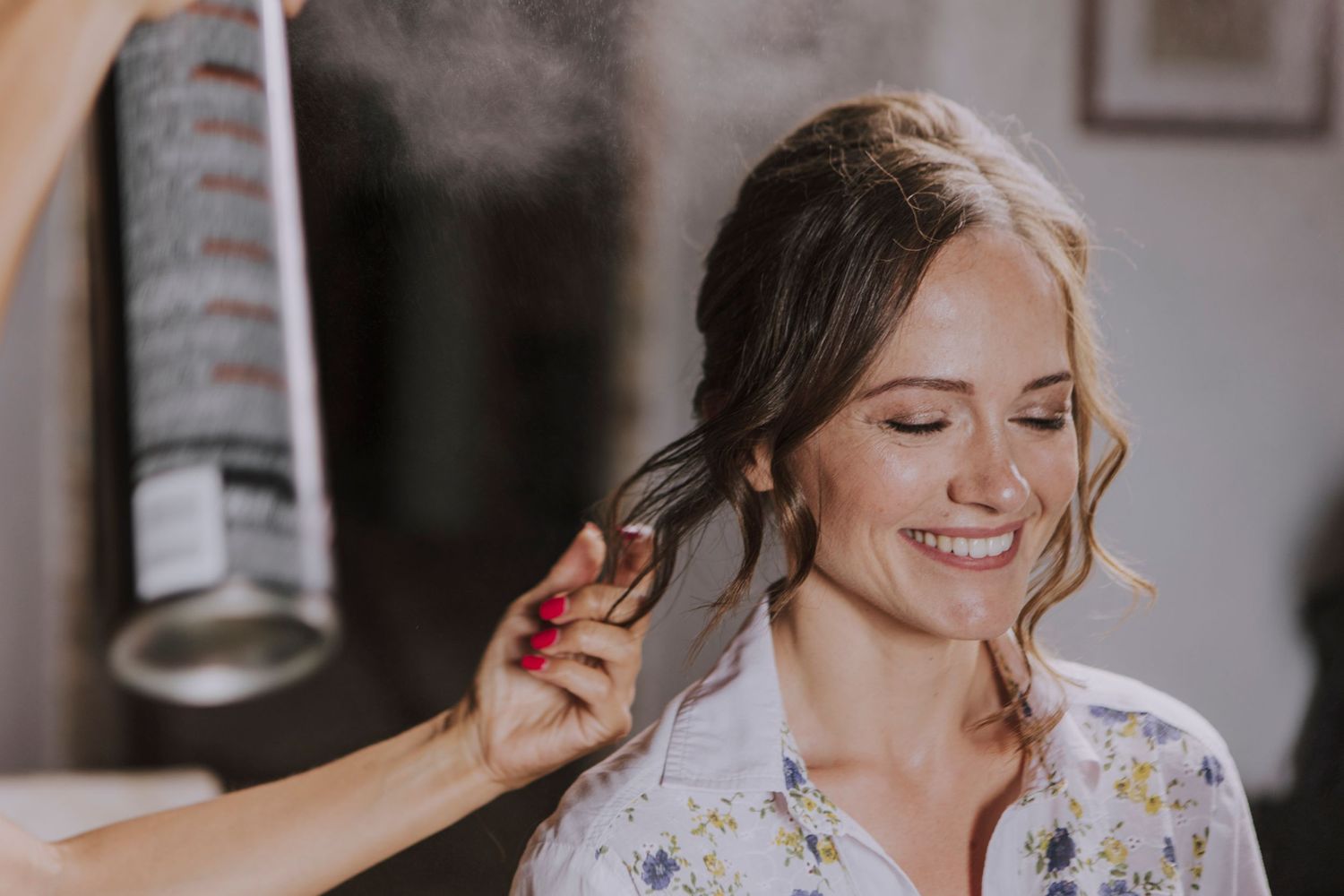 Hair styling moment during wedding preparations with soft natural lighting.